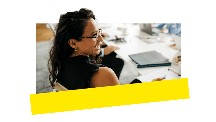 Una dipendente che si diverte mentre partecipa a una chiamata in una sala riunioni.